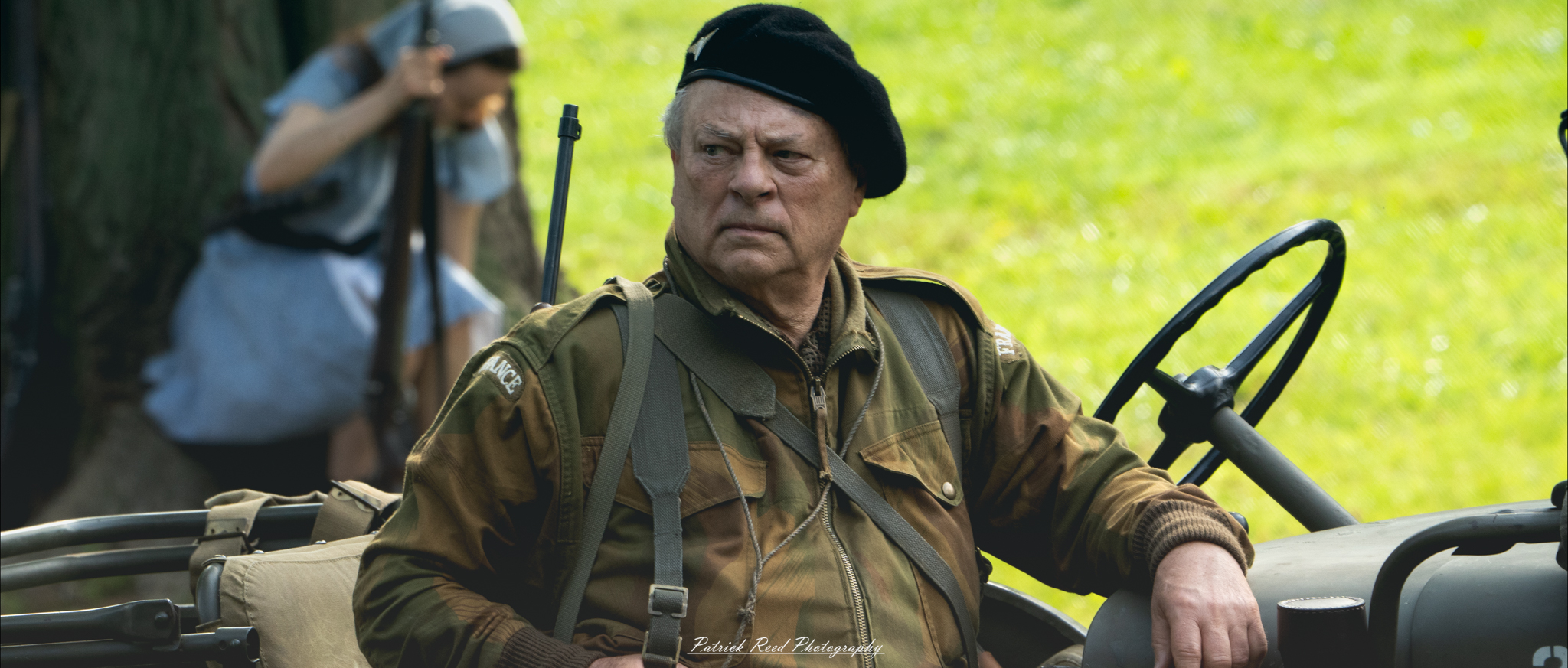 A striking image of an old commander sitting on a jeep, his face marked by years of experience. His stern gaze reflects authority and determination, capturing the weight of leadership in a moment of quiet intensity.
